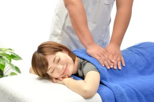 整体施術を受けてリラックスし、笑顔を見せる女性。健康をサポートする整体と笑顔の効果について説明する記事に最適なビジュアル。