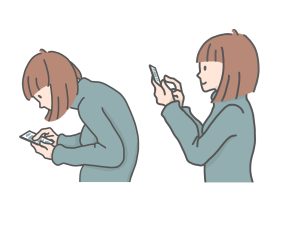 スマートフォンを見ながら猫背になっている若者