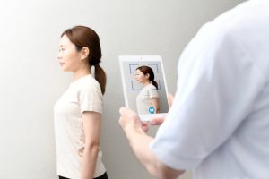 壁に背中をつけて正しい姿勢を確認する女性