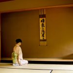 室で正座する和服の人物