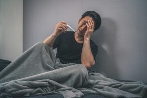 布団の中で体調不良に苦しむ人